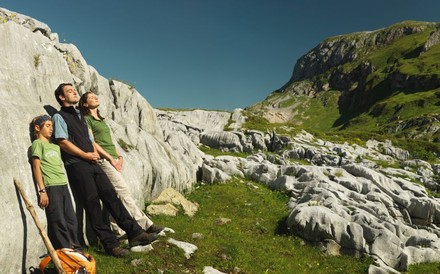 Familie ruht sich beim Wandern an eine Felswand gelehnt aus