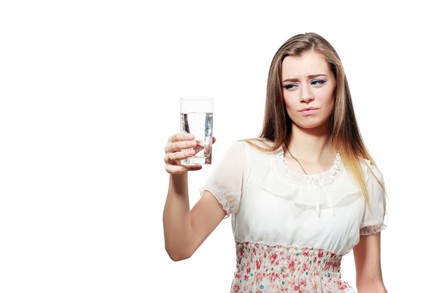 Frau sieht fragend auf Wasserglas