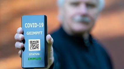 Älterer Herr zeigt digitalen Impfpass auf dem Smartphone, auf dem eine COVID-19 Impfung nachgewiesen wird