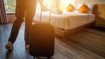 Gast mit Rollkoffer betritt das sonnendurchflutete Zimmer