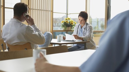 drei Ärzte sitzen in einer Kantine und trinken Kaffee