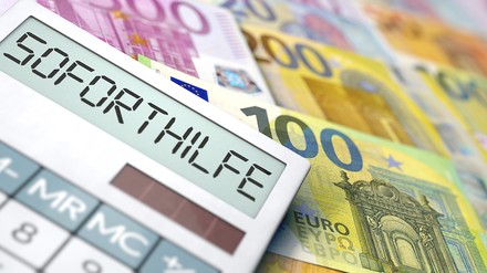 Taschenrechner mit dem Wort Soforthilfe im Sisplay, im Hintergrund liegen Euro-Geldscheine