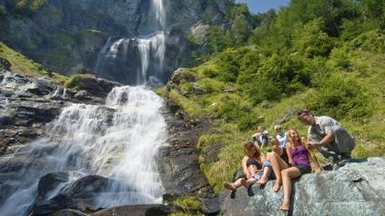 FReundesrunde macht Pause beim Wandern neben einem Wasserfall