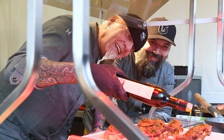 Zwei bärtige Männer marinieren ein paar Steaks auf einem Grill