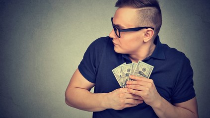 Geiziger Mann schnappt sich Geldbündel und behält es.