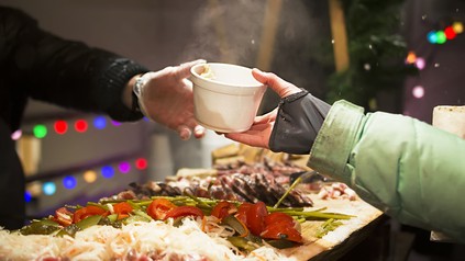 Eine Hand überreicht eine Essschale einer anderen Hand