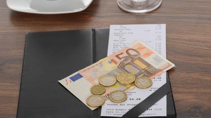 Rechnung, auf der ein 50 Euro Schein und mehrere Euromünzen liegen