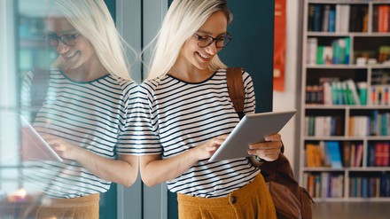 Frau in Bücherei lernt auf Tablet