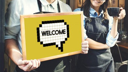 Mann hält Schild mit Inschrift "Welcome"