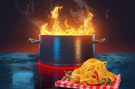 Eine Portion Pasta vor einem brennenden Topf