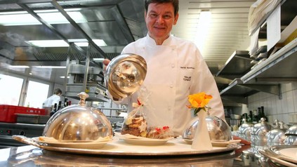 Drei-Sterne-Koch Harald Wohlfahrt posiert mit einem Tablett in der Küche des Restaurants Schwarzwaldstube