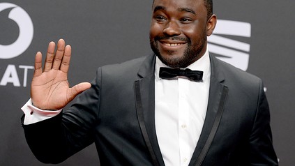 Spitzenkoch Nelson Müller im Anzug winkt einem Publikum zu