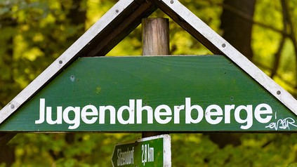 Grünes Holzschild auf dem das Wort Jugendherberge steht