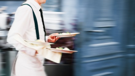 Kellner bringt Teller aus der Küche