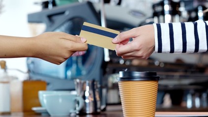 Eine Frau bezahlt einen Kaffee mit Karte