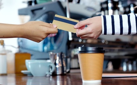 Eine Frau bezahlt einen Kaffee mit Karte