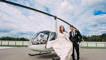 Ein Hochzeitspaar vor einem Hubschrauber mit Pilot