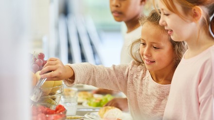 Schulkinder, die sich am Buffet etwas zu essen holen
