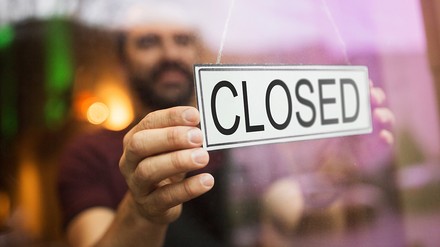 Mann hängt ein Closed-Schild in die Glastür oder in das Fenster eines Restaurants