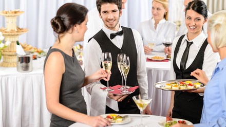 Zwei Service-Kräfte reichen Getränke und Snacks