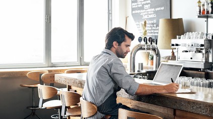 Gastronom an der Theke mit Pc, Block und Stift